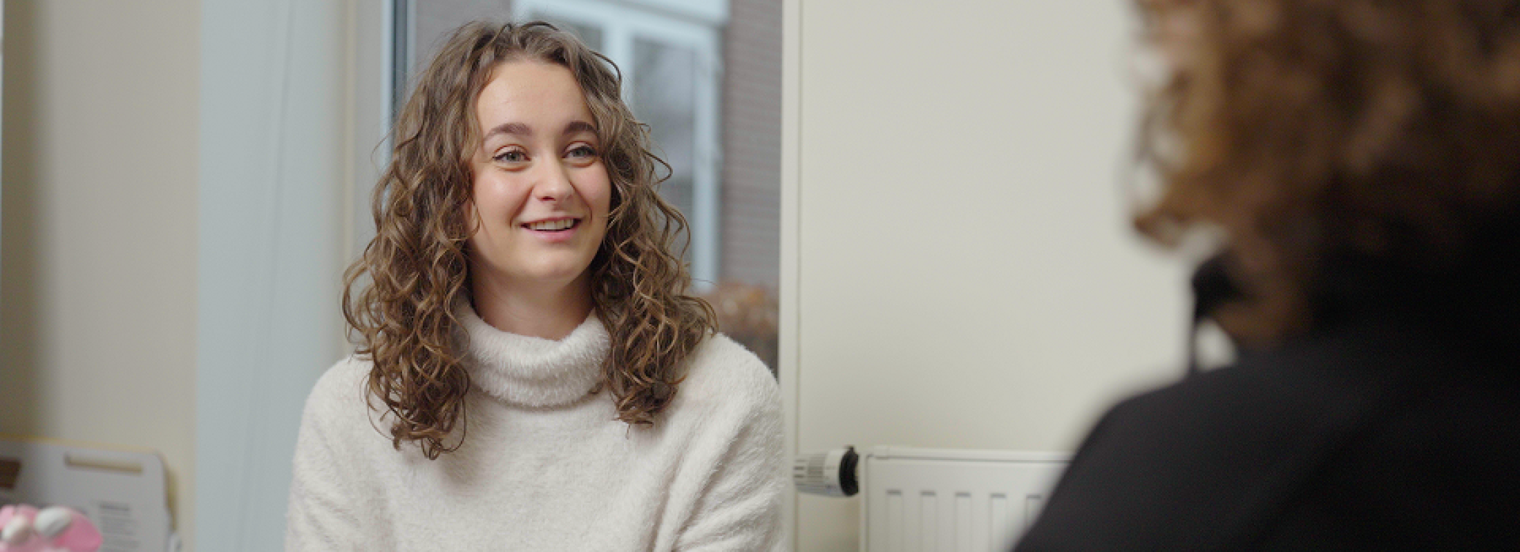 Blijf op de hoogte van de nieuwe kliniek van IrisZorg! Vrouw lacht naar iemand anders